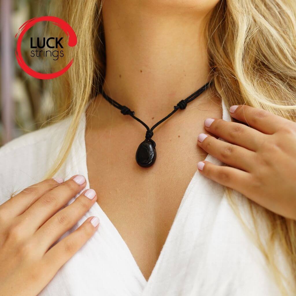 Luck Strings woman in white top wearing a black Tourmaline pendant.
