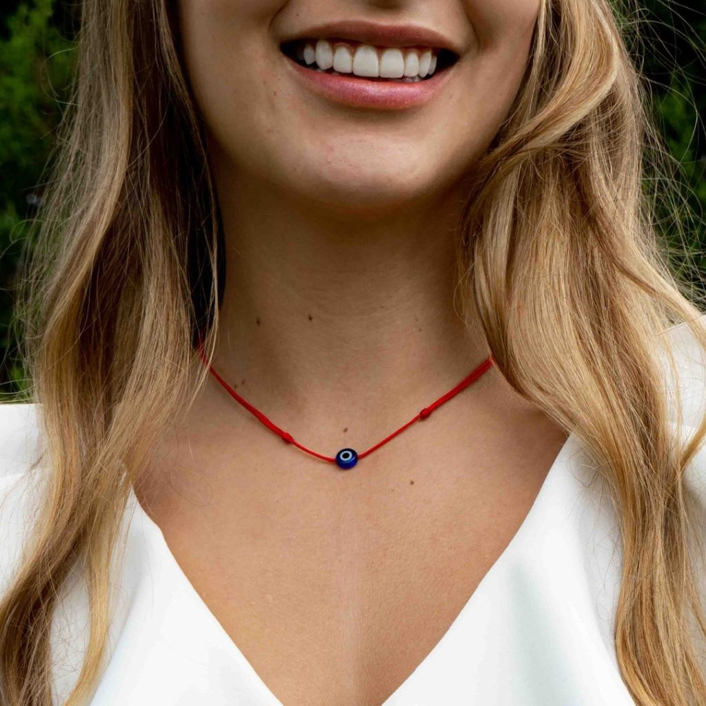 Woman elegantly wearing an Evil Eye Choker Necklace, showcasing its vibrant eye symbol that adds a touch of mystical charm to her outfit - Luck Strings