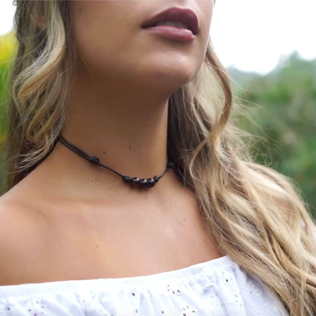Close-up of a garnet choker adorning a woman's neck, with the deep red gemstones drawing attention, offered by Luck Strings.