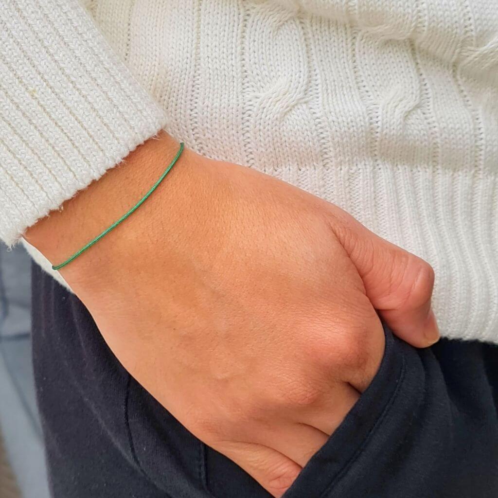 Casual look with a person wearing a green string gold clasp bracelet with a white shirt - Luck Strings.