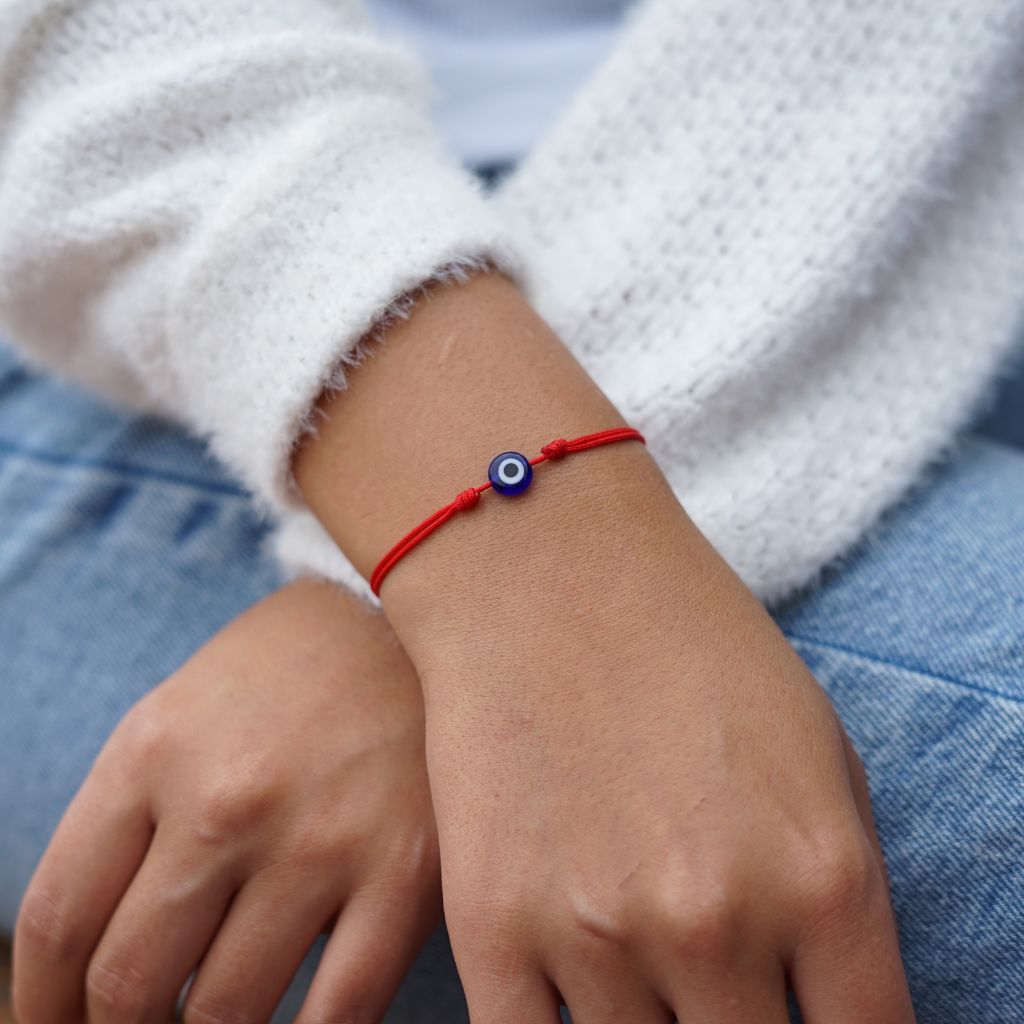 Woman wearing a delicate evil eye bracelet, showcasing its elegant and protective design. - Luck Strings