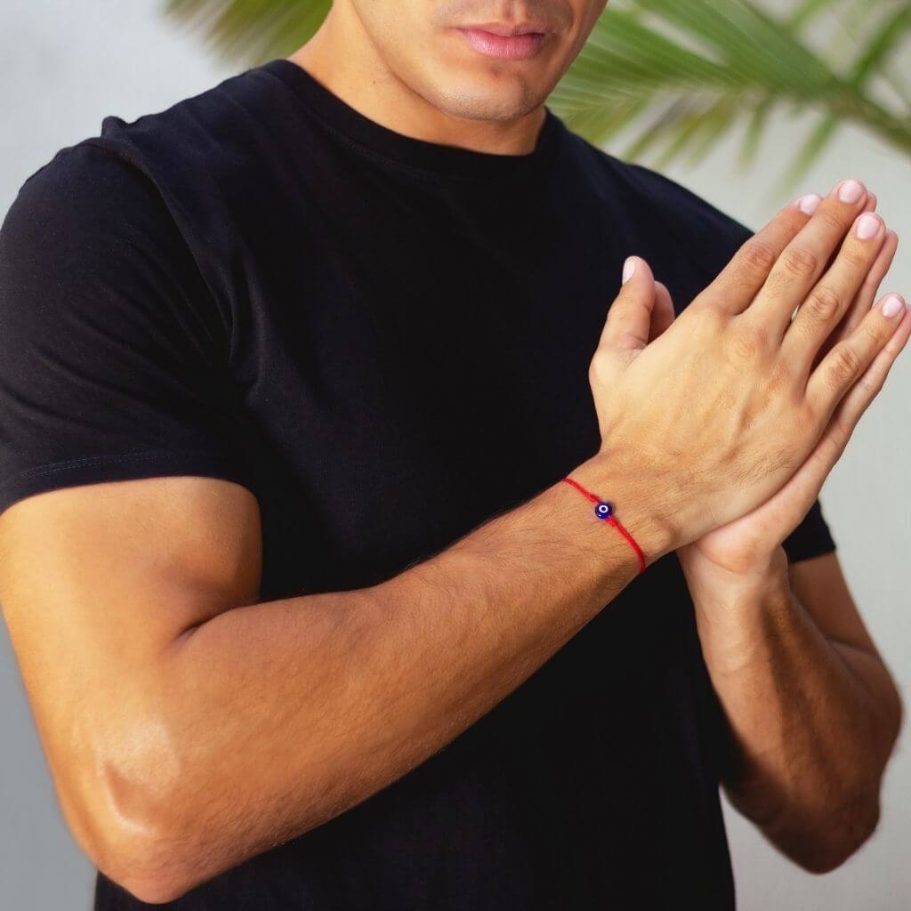 Man wearing a minimalist red cord evil eye bracelet, showcasing a subtle yet stylish protective accessory. - Luck Strings