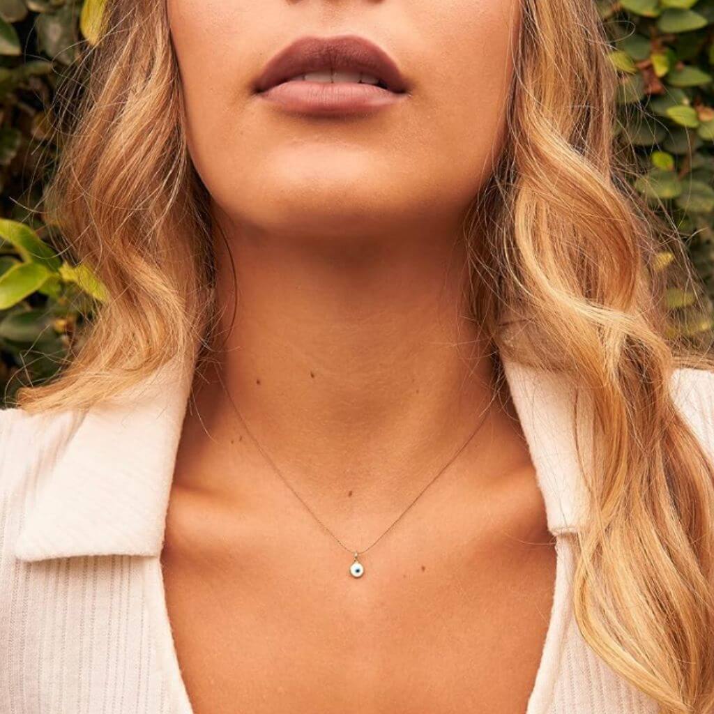 Woman gracefully wearing the Gold Turkish Evil Eye Silk Choker, its glass gold eye charm adding a touch of refined protection to her ensemble - Luck Strings.