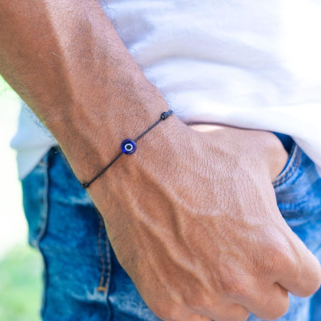 Man wearing a minimalist red cord evil eye bracelet, showcasing a subtle yet stylish protective accessory. - Luck Strings