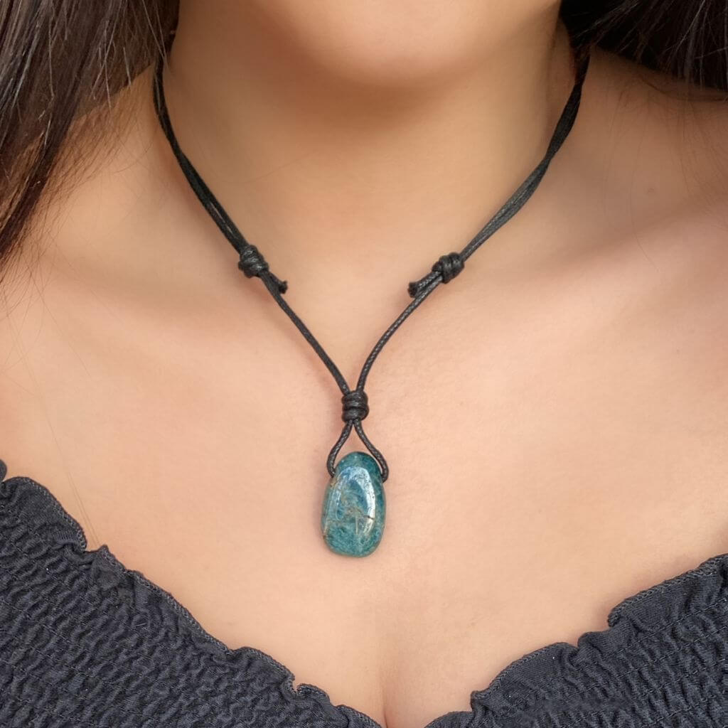 Luck Strings blue-green apatite pendant on an adjustable leather cord necklace worn by a woman.lace with a blue-green apatite pendant
