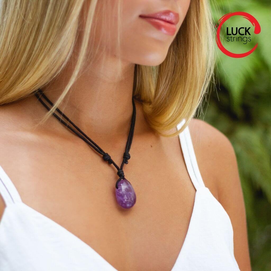 Woman gracefully wearing a Luck Strings Amethyst necklace, the crystal's violet hue complementing her elegant attire