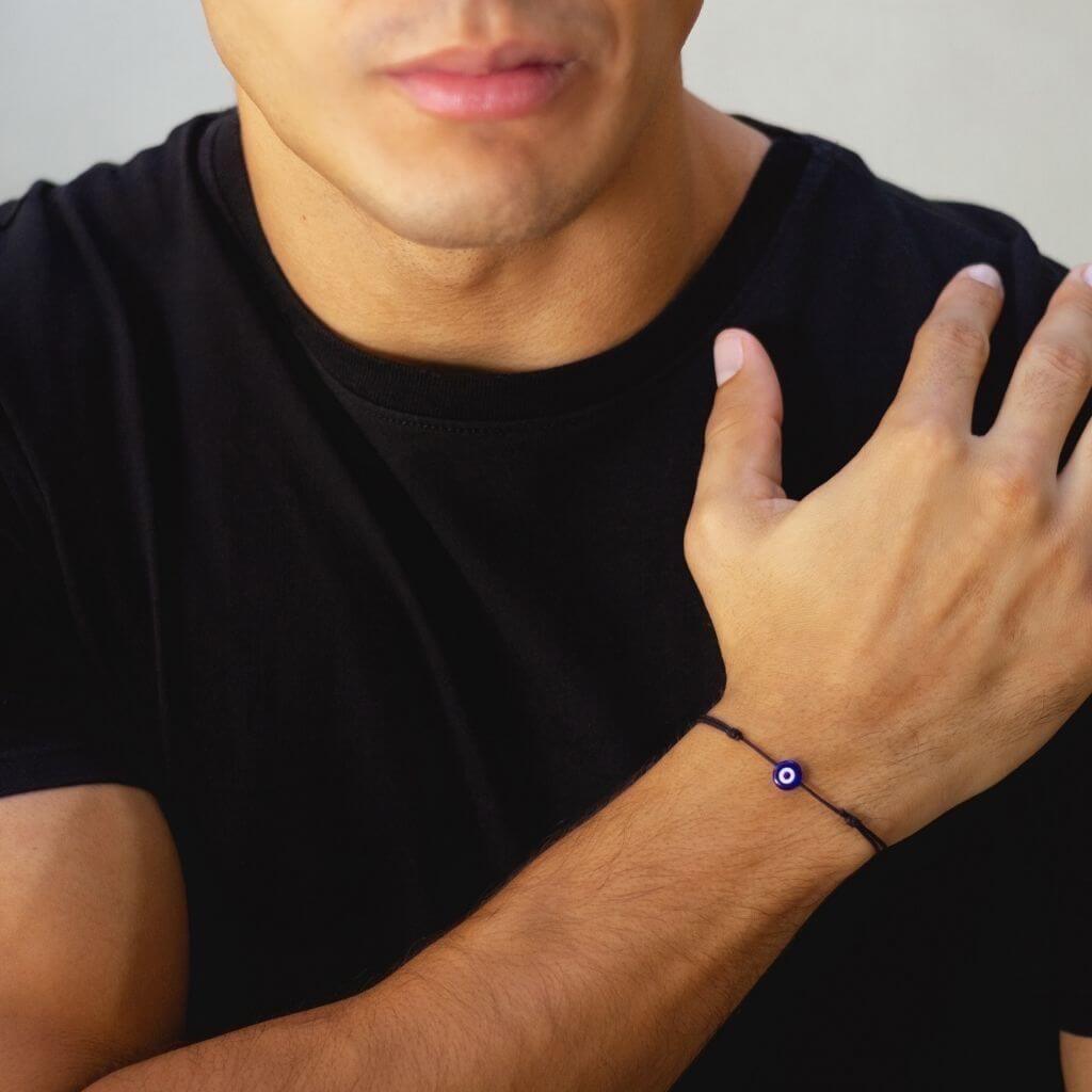 Man wearing a minimalist red cord evil eye bracelet, showcasing a subtle yet stylish protective accessory. - Luck Strings