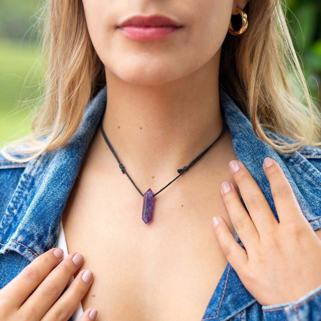 Woman elegantly wearing the Unisex Amethyst Crystal Point Necklace, symbolizing peace and style - Luck Strings.