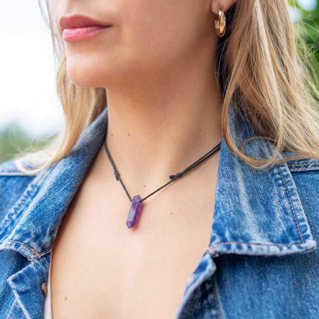 Woman elegantly wearing the Unisex Amethyst Crystal Point Necklace, symbolizing peace and style - Luck Strings.