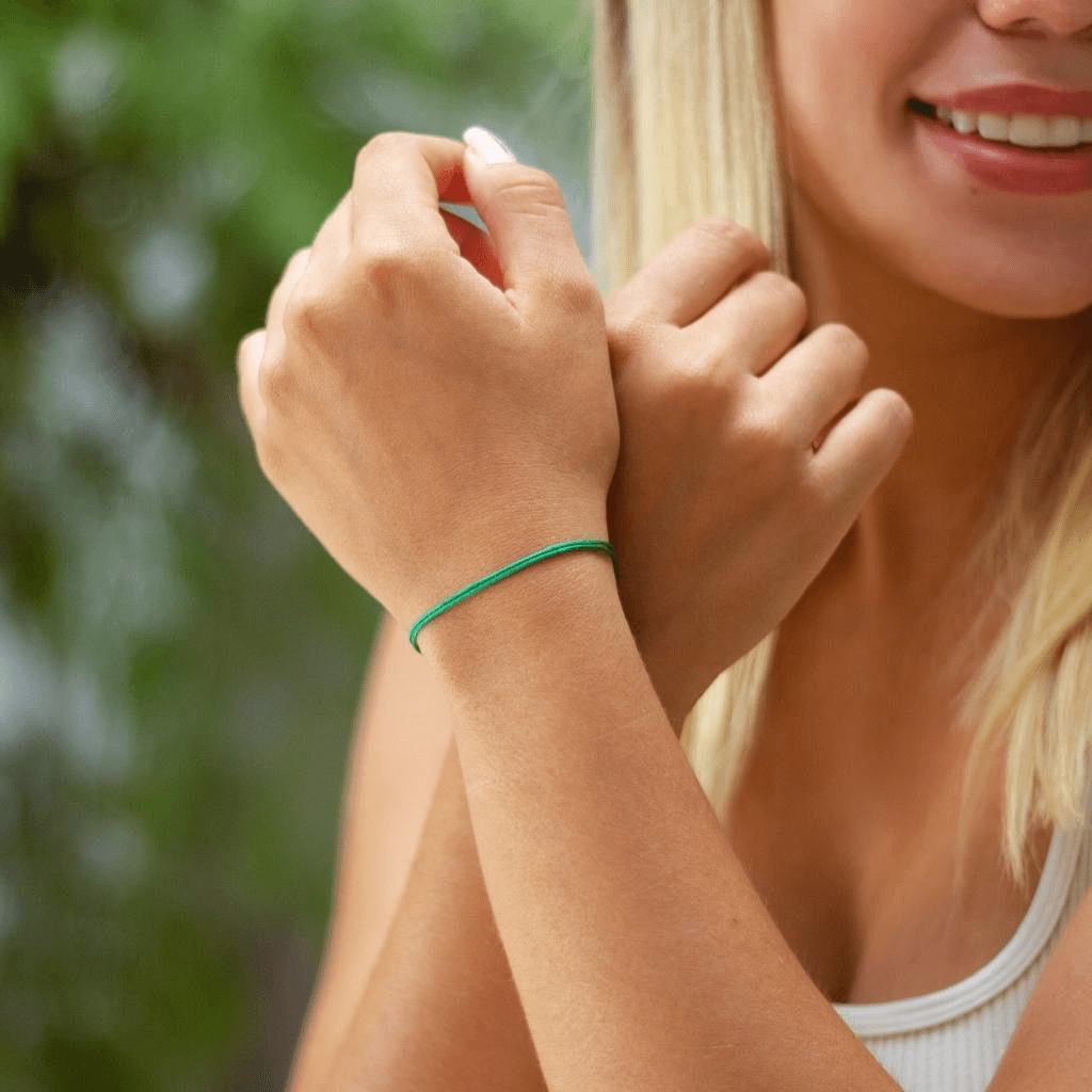 Adjustable green cord bracelet on woman&#39;s wrist by Luck Strings
