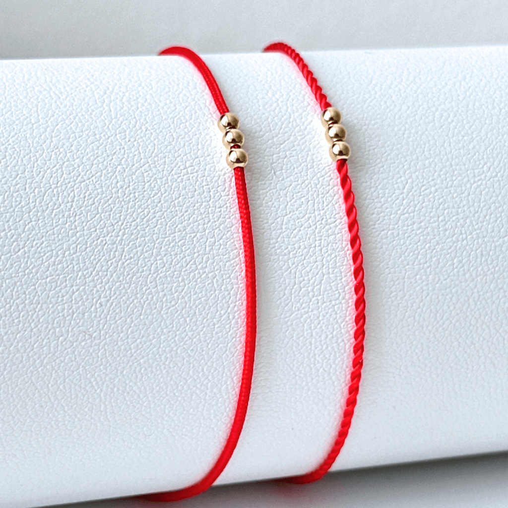 Red cord bracelet with three solid gold beads and a secure clasp, showcasing a minimalist and elegant design. - Luck Strings