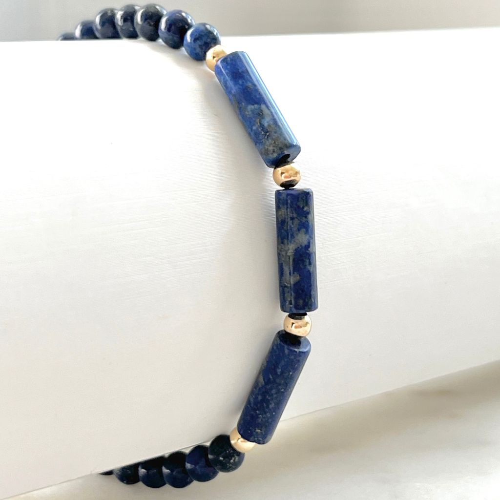Lapis Lazuli 14K Gold Bracelet draped over a surface, showcasing the rich blue beads and luxurious gold details - a sophisticated piece by Luck Strings.
