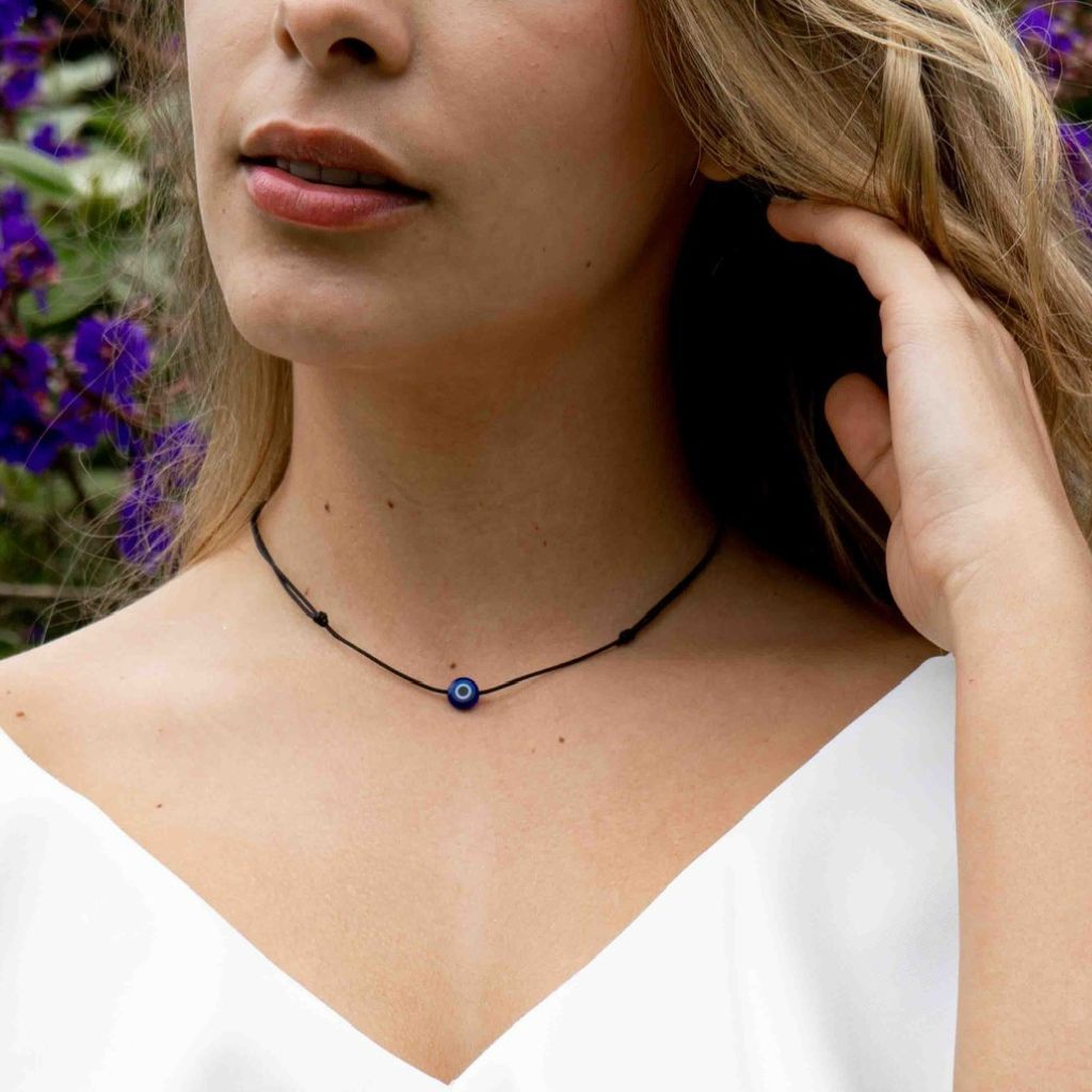 Woman elegantly wearing an Evil Eye Choker Necklace, showcasing its vibrant eye symbol that adds a touch of mystical charm to her outfit - Luck Strings