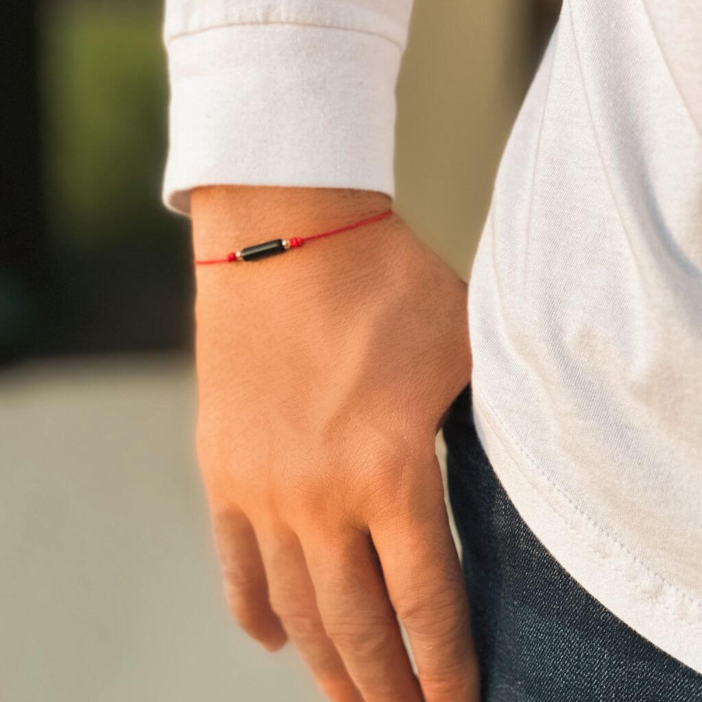 Person adjusting their 14K Gold Black Tourmaline Red String Bracelet for a perfect fit - Luck Strings