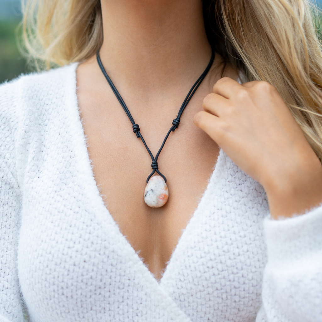 Woman wearing a Sunstone necklace with adjustable black cord over a white sweater - Luck Strings