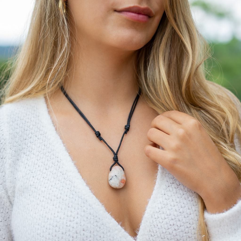 Woman wearing a Sunstone necklace with adjustable black cord over a white sweater - Luck Strings