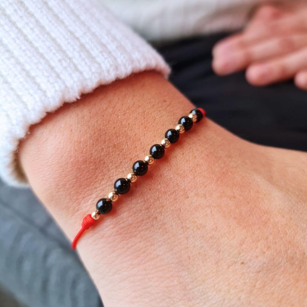 Man wearing a Black Tourmaline & 14K Gold Red Bracelet, showcasing the elegant blend of the protective black stone and luxurious gold accents - Luck Strings.