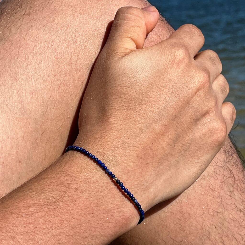 Man showcasing a Lapis Lazuli & 14K Solid Gold Minimalist Bracelet on his wrist, highlighting the rich blue lapis against the luxurious gold - Luck Strings.