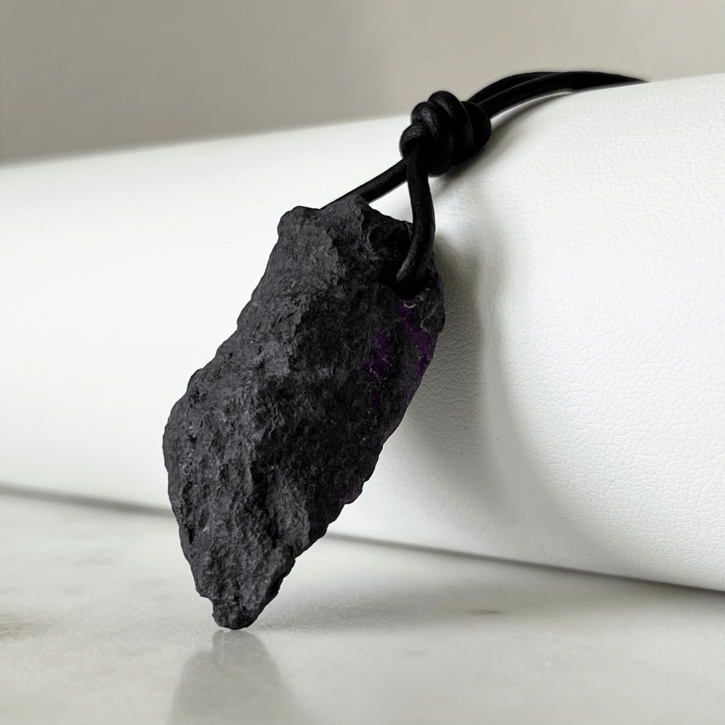 A one-of-a-kind Raw Sugilite Gemstone Pendant showcasing its distinctive deep purple color, suspended from a sleek cord, symbolizing spiritual growth and emotional healing - Luck Strings.