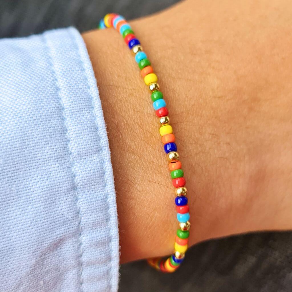 Man displaying a 14K Gold Rainbow Beaded Bracelet on his wrist, showcasing its unisex and elegant style - Luck Strings