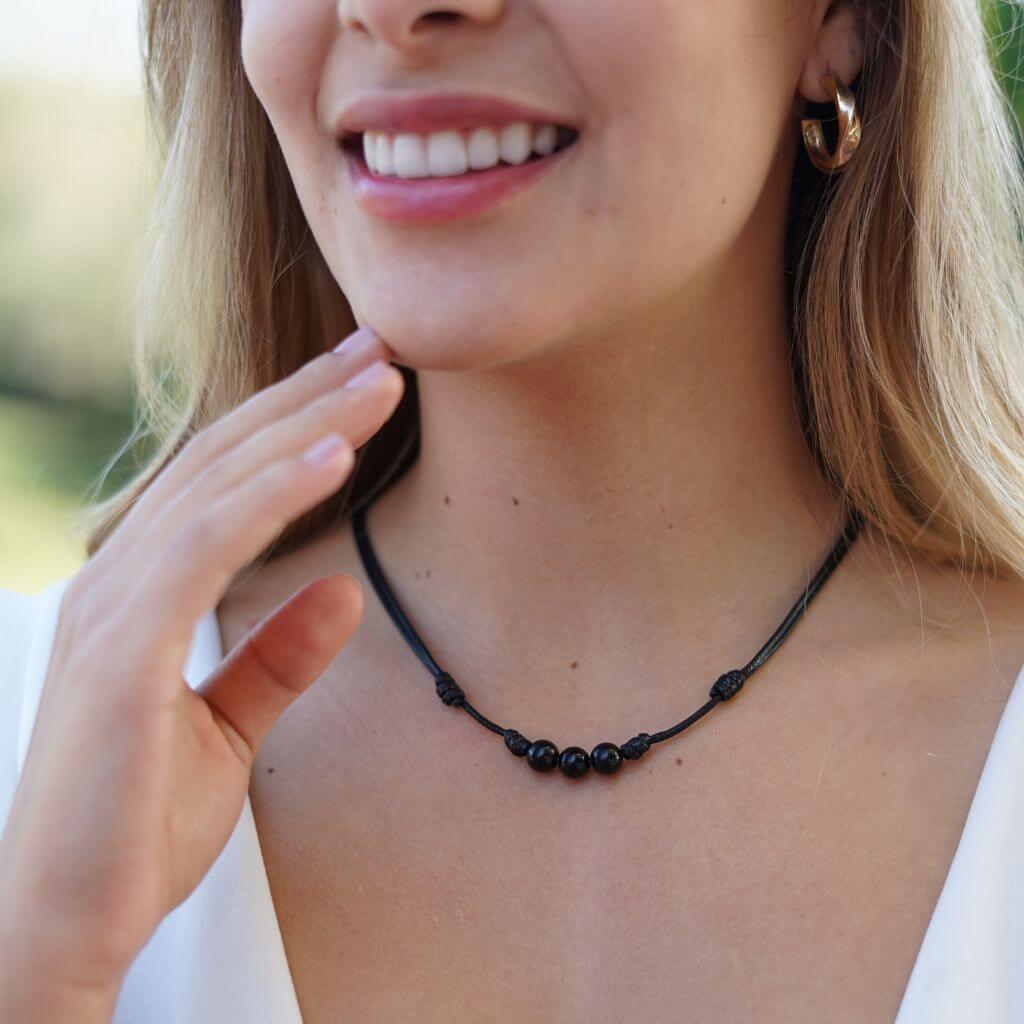 Woman wearing a Black Tourmaline Beaded Choker, showcasing its elegant black beads that add a sophisticated touch to her outfit - Luck Strings