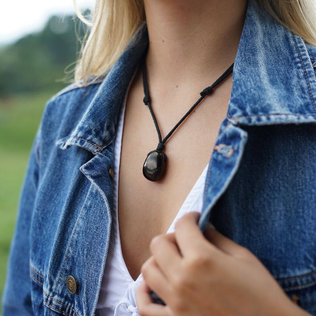 A woman elegantly wearing the Luck Strings Jet Stone Necklace, showcasing its deep black color and timeless design 