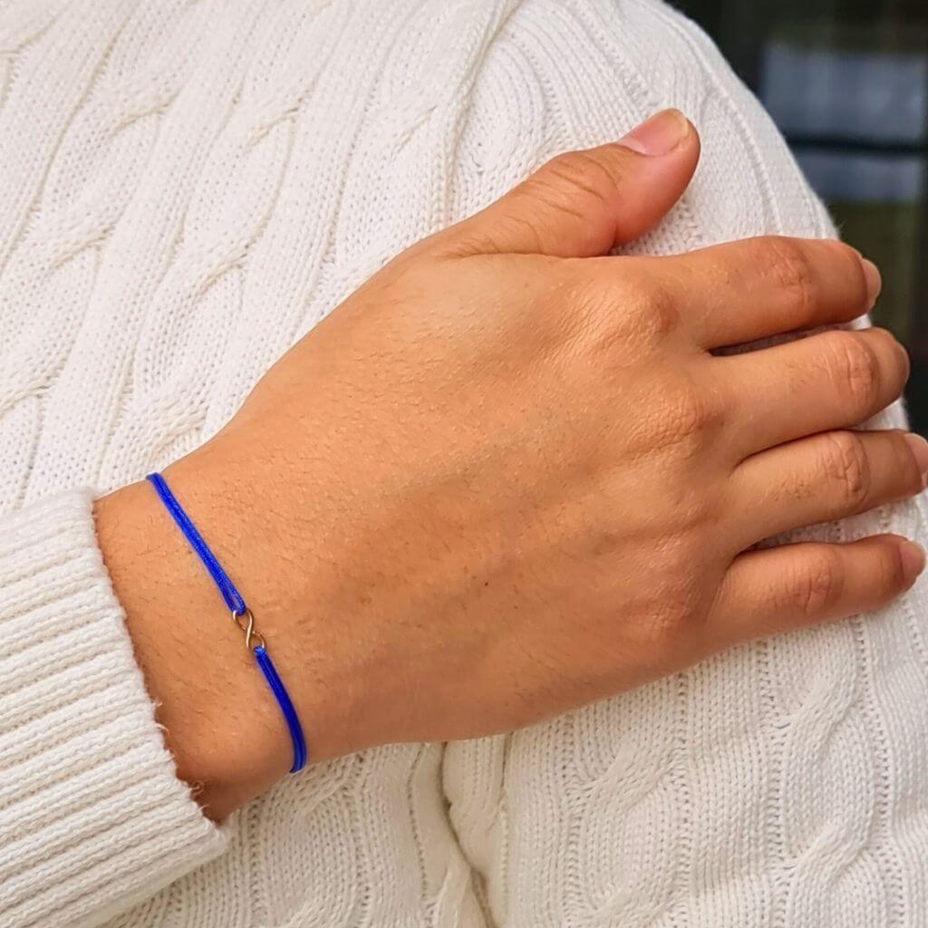 man with a Petite 14K Gold Infinity Bracelet from Luck Strings, demonstrating the bracelet's versatile and sophisticated appeal on his wrist.