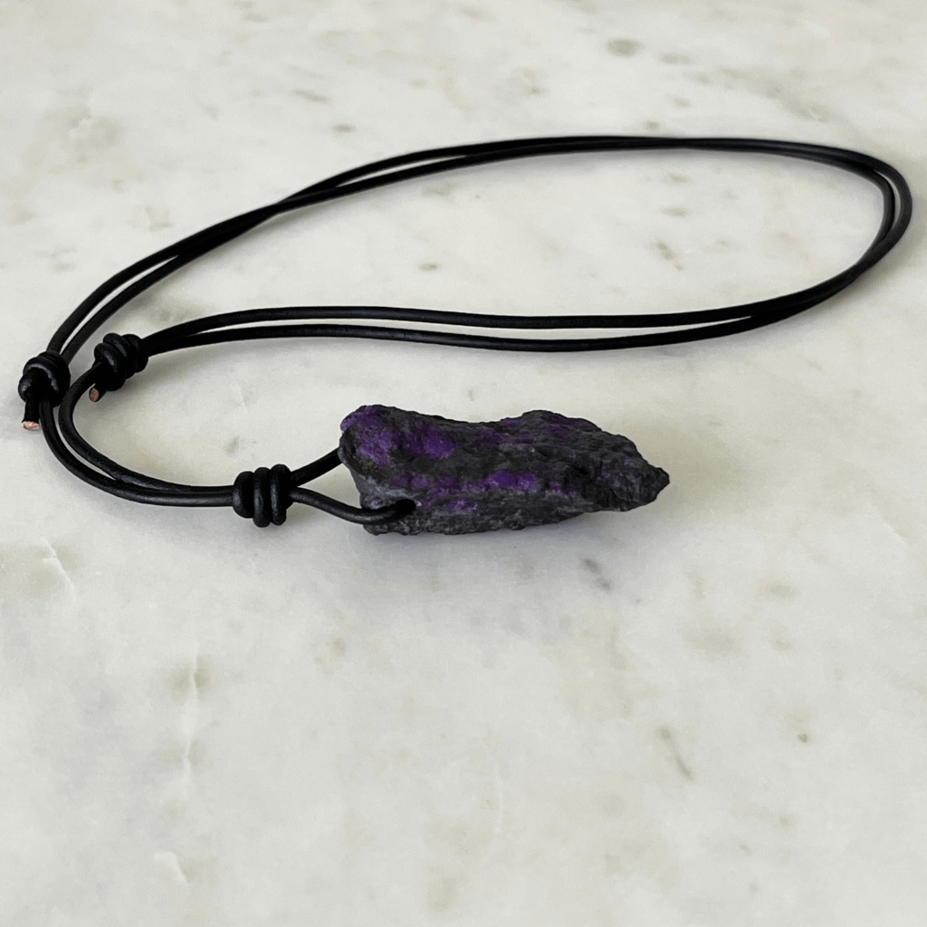 A one-of-a-kind Raw Sugilite Gemstone Pendant showcasing its distinctive deep purple color, suspended from a sleek cord, symbolizing spiritual growth and emotional healing - Luck Strings.