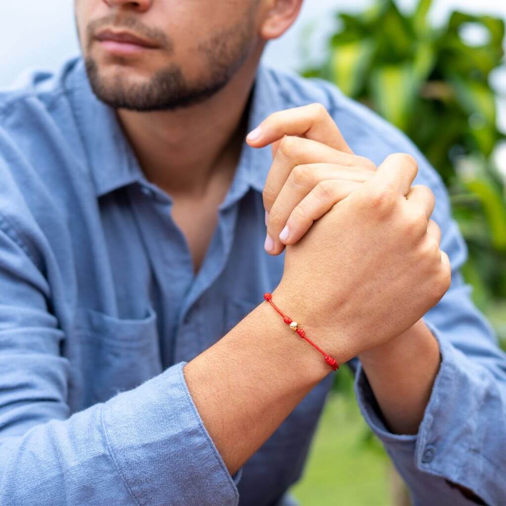 Man showcasing a red string bracelet with 14K yellow gold beads - Luck Strings