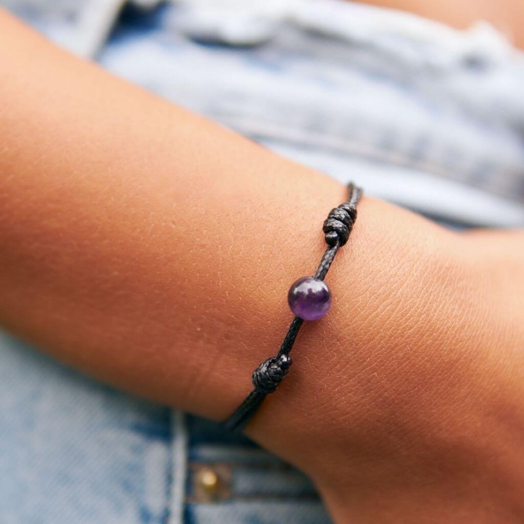 Woman gracefully wearing the Amethyst Beaded Bracelet, reflecting its serene beauty and calming elegance - Luck Strings