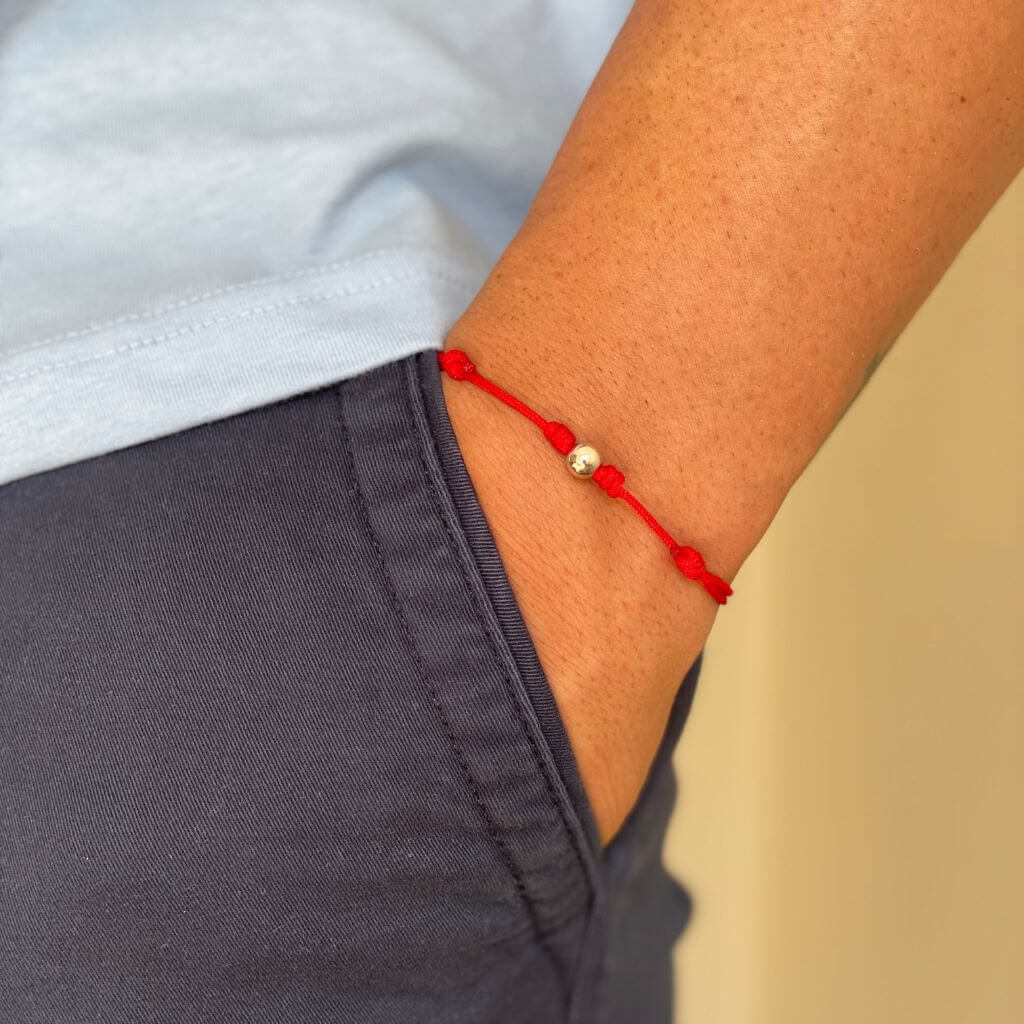 Man showcasing a red string bracelet with 14K yellow gold bead - Luck Strings