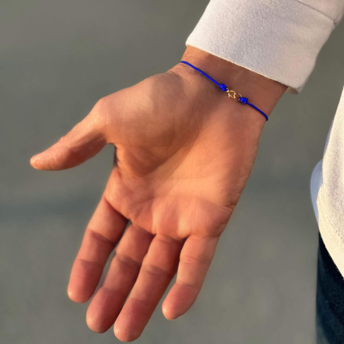 Stylish blue string bracelet with a gold accent worn casually - Luck Strings.