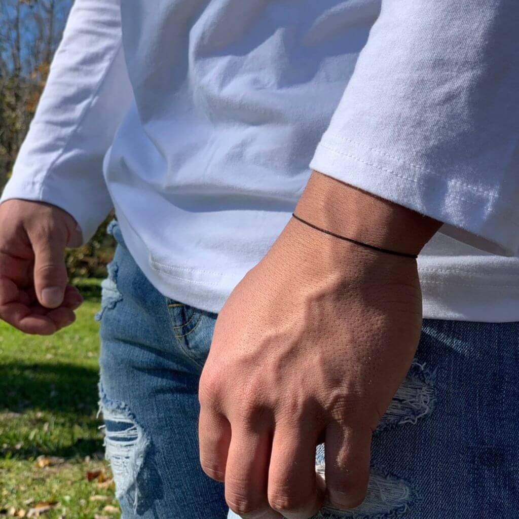 Man wearing a black string bracelet, emphasizing its unisex and versatile design - Luck Strings