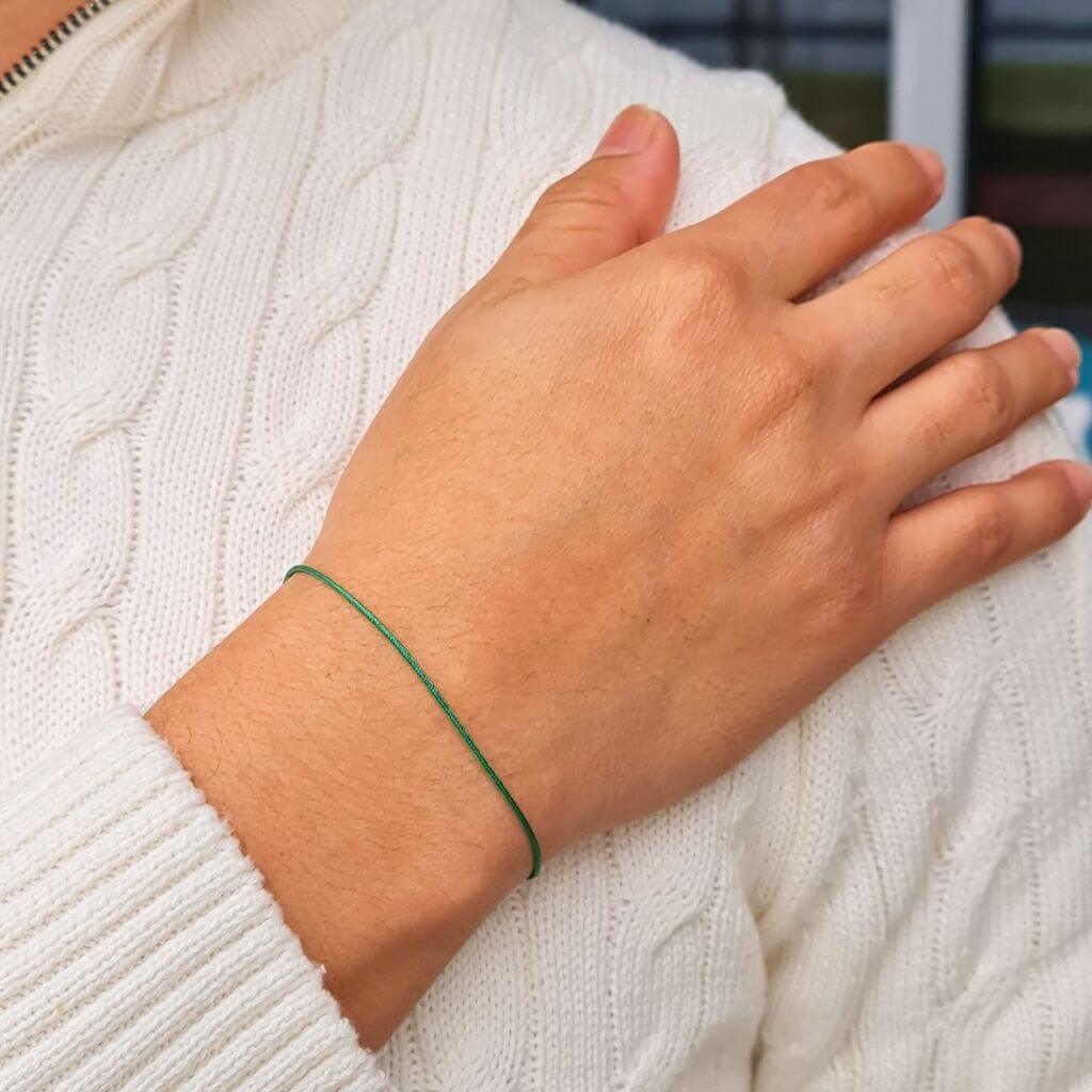 Casual look with a person wearing a green string gold clasp bracelet with a white shirt - Luck Strings.