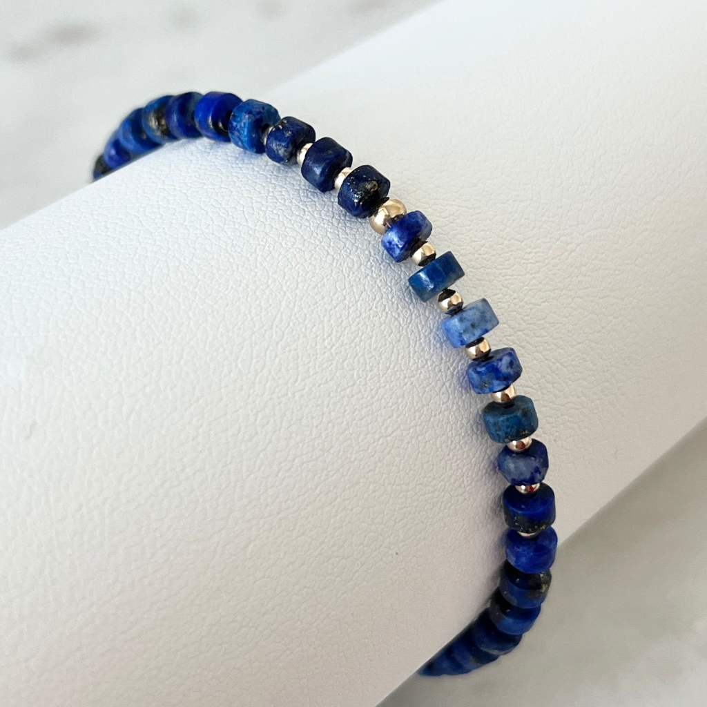 Close-up image of the Lapis Lazuli Cylinder &amp; 14K Gold Minimalist Bracelet, showcasing its elegant design with deep blue lapis lazuli beads and sparkling 14K gold accents, embodying sophisticated simplicity - Luck Strings