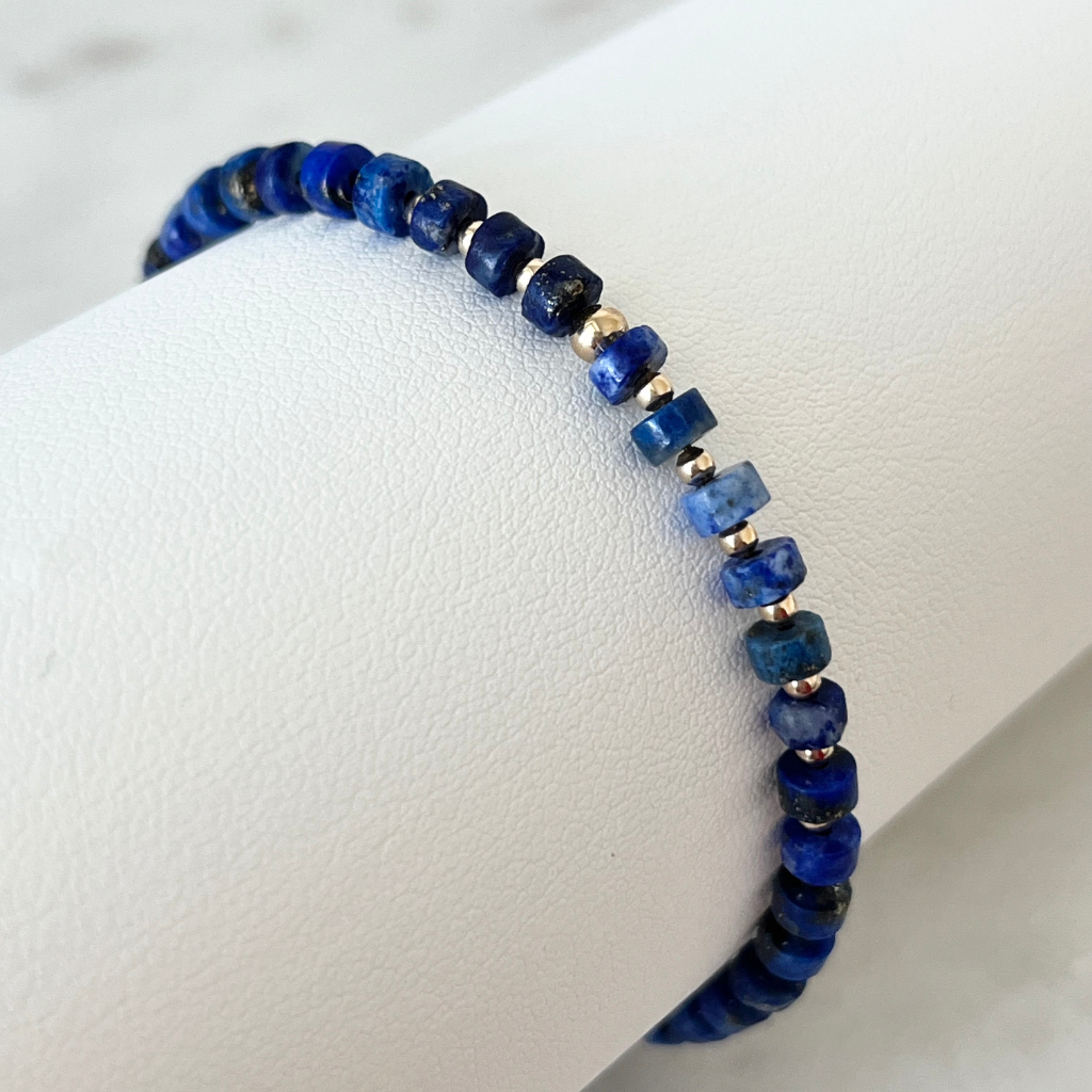 Close-up image of the Lapis Lazuli Cylinder & 14K Gold Minimalist Bracelet, showcasing its elegant design with deep blue lapis lazuli beads and sparkling 14K gold accents, embodying sophisticated simplicity - Luck Strings