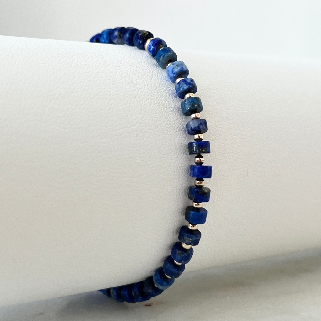 Close-up image of the Lapis Lazuli Cylinder & 14K Gold Minimalist Bracelet, showcasing its elegant design with deep blue lapis lazuli beads and sparkling 14K gold accents, embodying sophisticated simplicity - Luck Strings