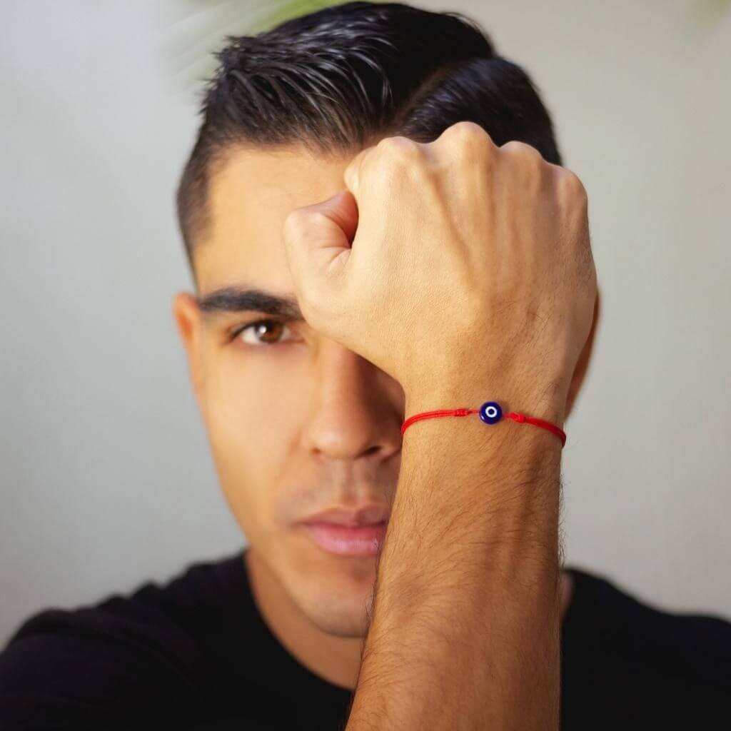 Man wearing a minimalist red cord evil eye bracelet, showcasing a subtle yet stylish protective accessory.-Luck Strings