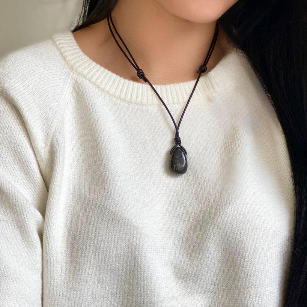 Model wearing a dark Nuummite adjustable necklace by Luck Strings against a light sweater, exemplifying elegant simplicity.