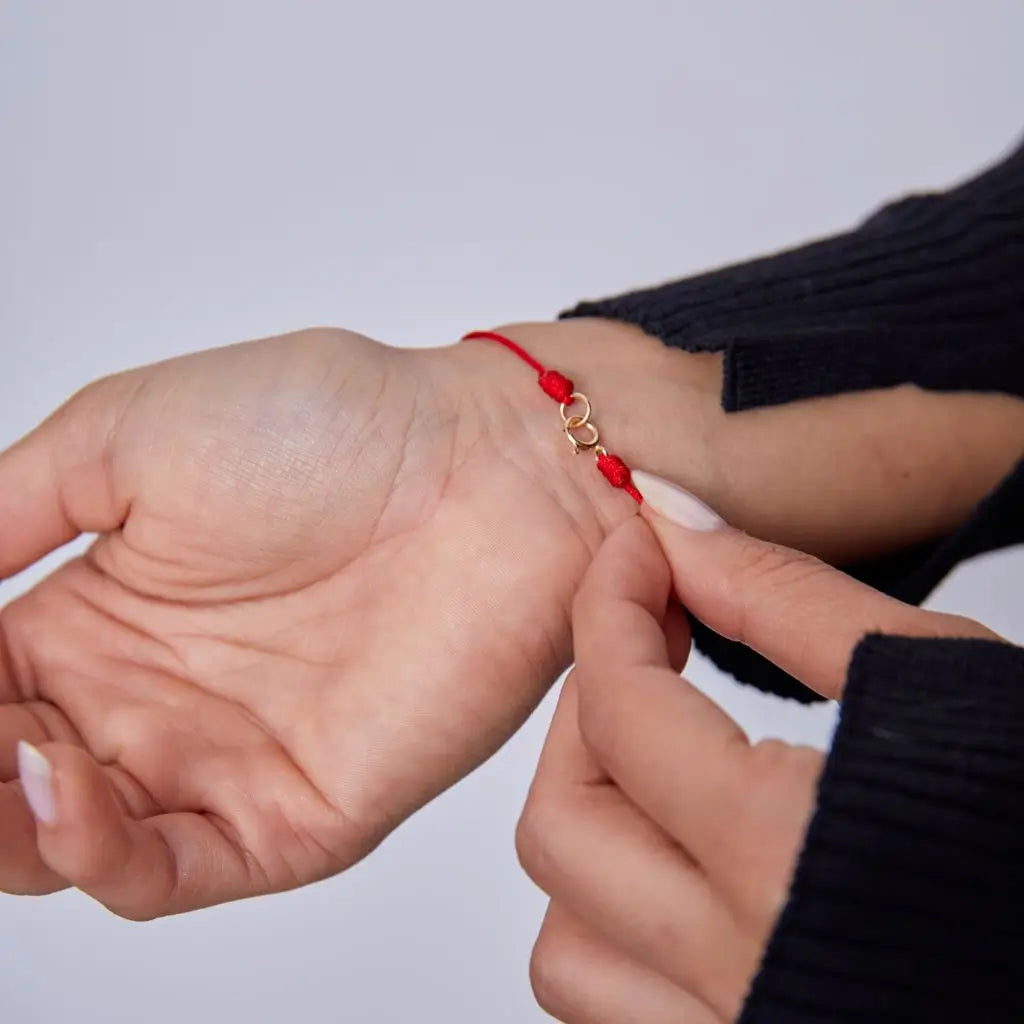 Woman wearing a classic red string bracelet with a 14K solid gold clasp on their wrist - Luck Strings