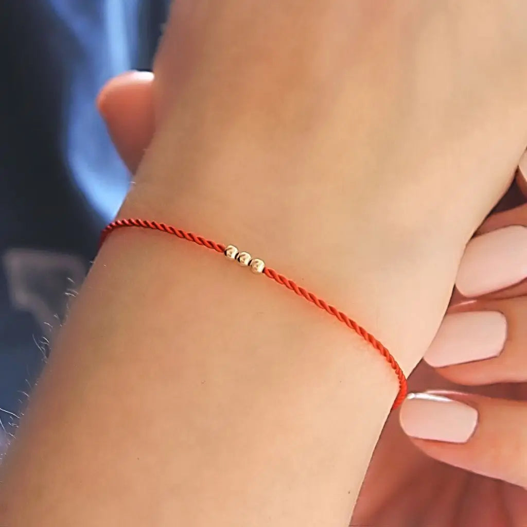 Red silky cord bracelet with three solid gold beads and a secure clasp, showcasing a minimalist and elegant design. - Luck Strings