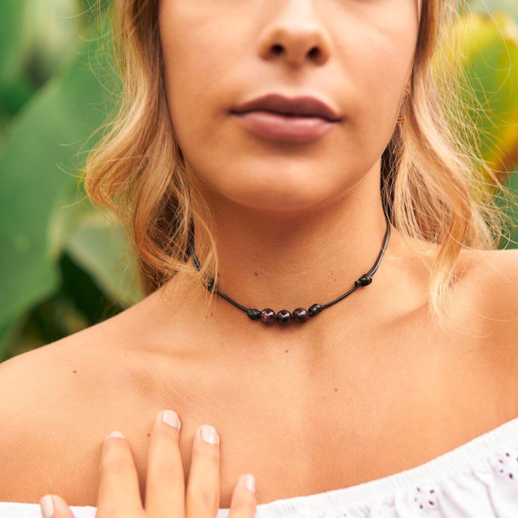 Luck Strings garnet beaded choker modeled against a soft pink blouse, highlighting the stones' rich color.