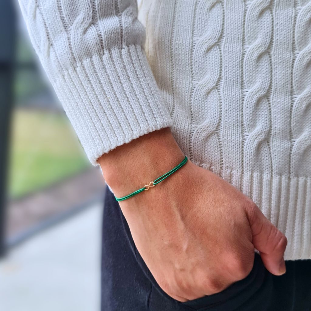 man with a Petite 14K Gold Infinity Bracelet from Luck Strings, demonstrating the bracelet's versatile and sophisticated appeal on his wrist.