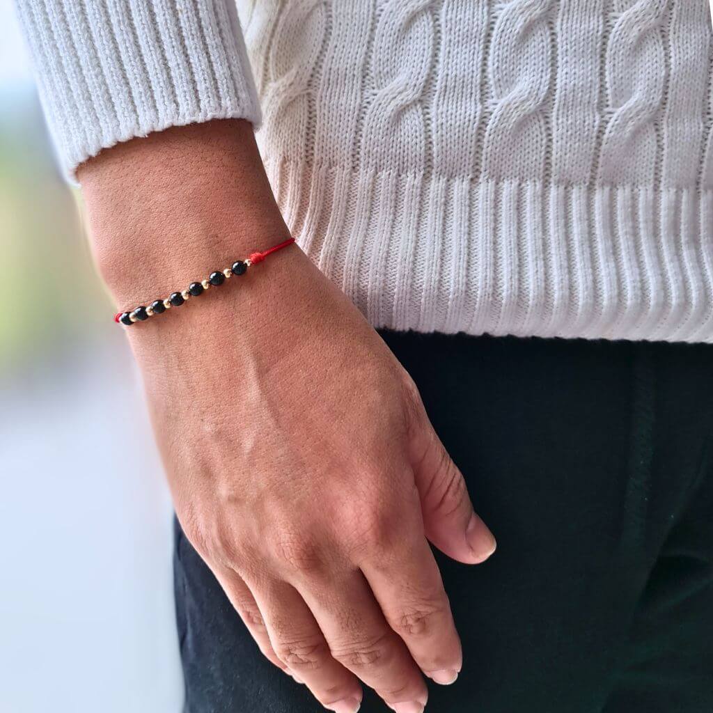 Man wearing a Black Tourmaline &amp; 14K Gold Red Bracelet, showcasing the elegant blend of the protective black stone and luxurious gold accents - Luck Strings.