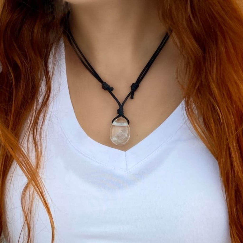 Clear Quartz pendant necklace worn by a woman in a flowing blouse, with the crystal catching and reflecting the light.-Luck Strings