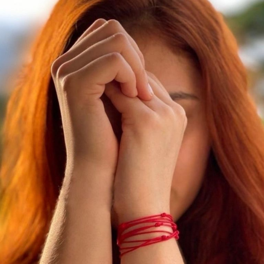 Woman showcasing her Six Red String Bracelets, each symbolizing unique protection and style - Luck Strings.