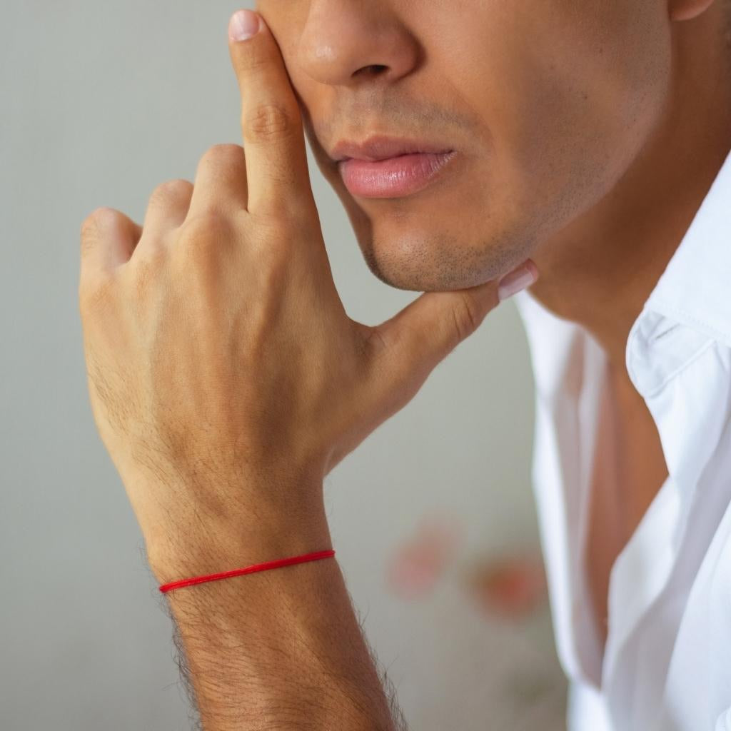 Man displaying a bracelet from the Two Pack Red String Bracelets, symbolizing connection and protection - Luck Strings