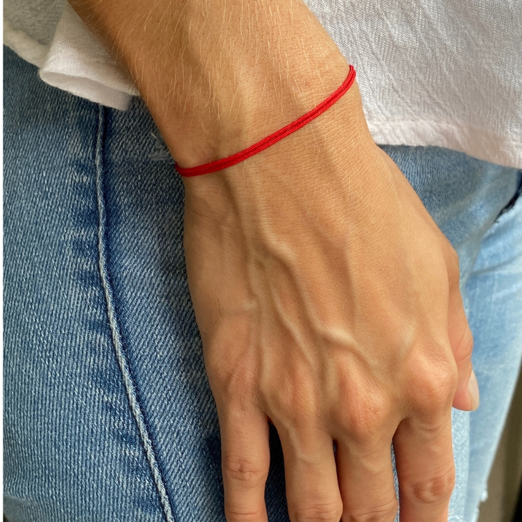 Woman showcasing her Red String Bracelet, symbolizing unique protection and style - Luck Strings