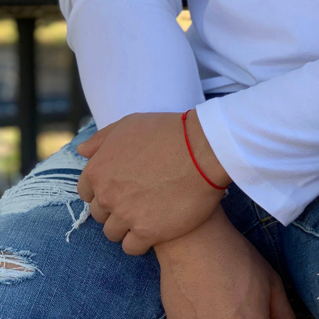 Man displaying a bracelet from the Two Pack Red String Bracelets, symbolizing connection and protection - Luck Strings