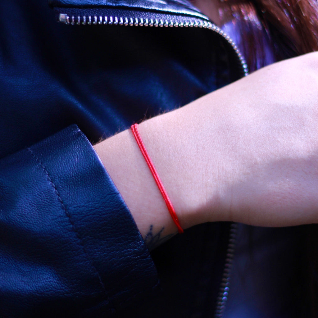 Woman showcasing her Red String Bracelet, symbolizing unique protection and style - Luck Strings.